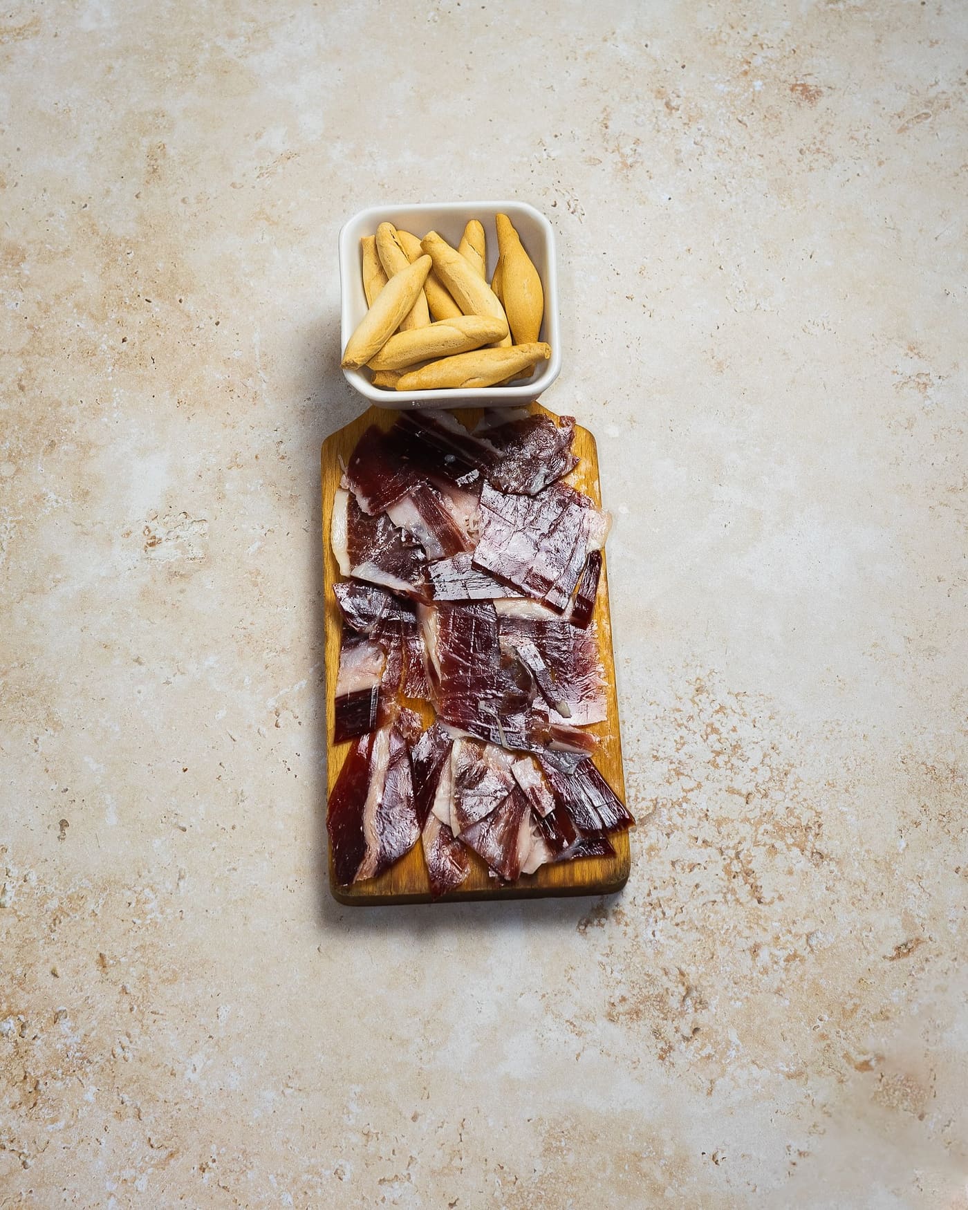 Jamon Iberico carved onto a wooden board with picos